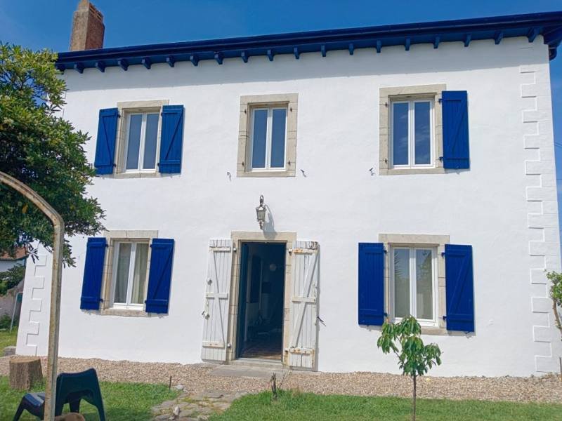 Maison ancienne enduite en blanc avec encadrements en pierre et volets bleus