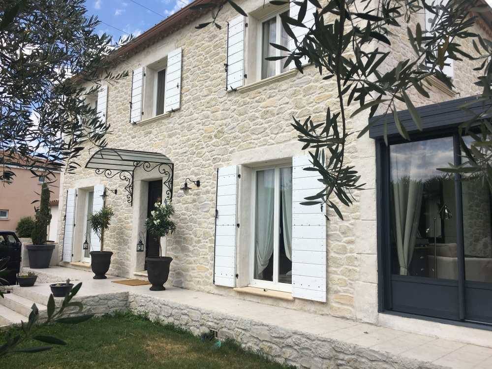 Façade en pierre apparente rejointoyée avec volets blancs et encadrements de fenêtres clairs